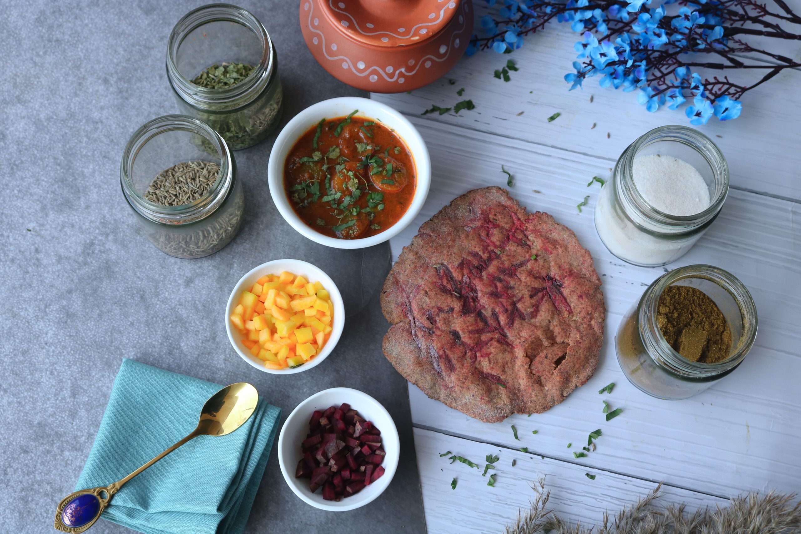 Top view of Indian dishes and spices featuring vibrant chutneys, breads, and herbs.