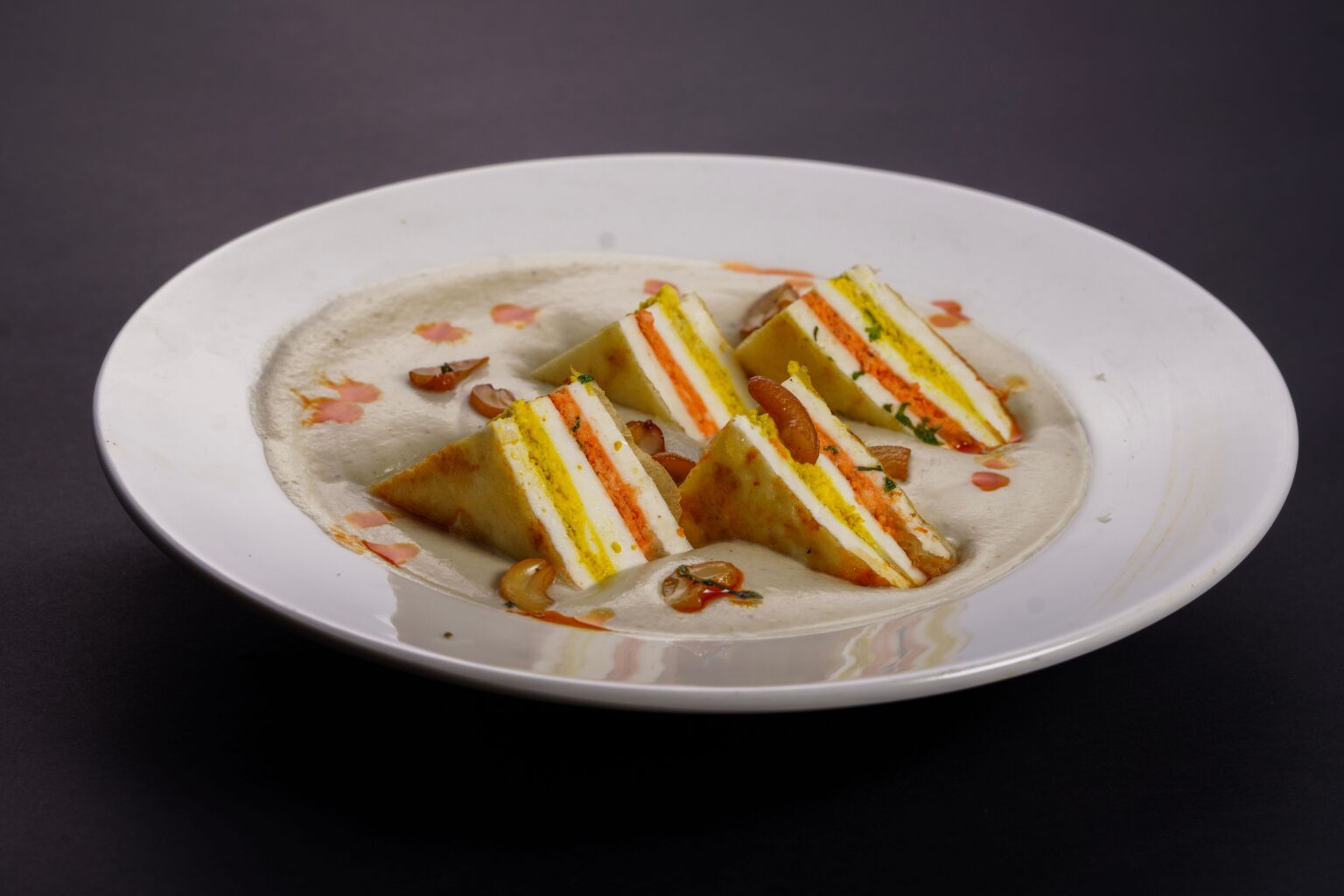 Delicious paneer dish with layered curry and cashew garnish, perfect for Indian cuisine lovers.